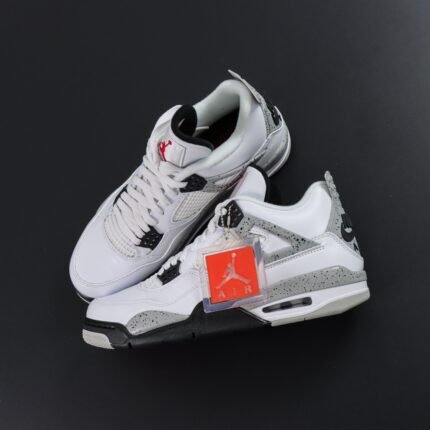 White sneakers with black and silver accents, red logo, on a black background