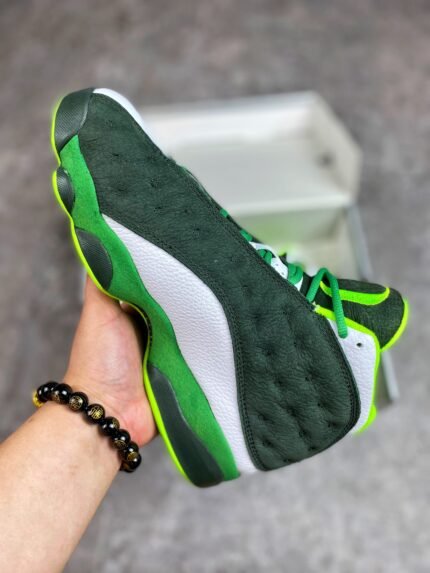 Green and white sports shoes, held in hand for display