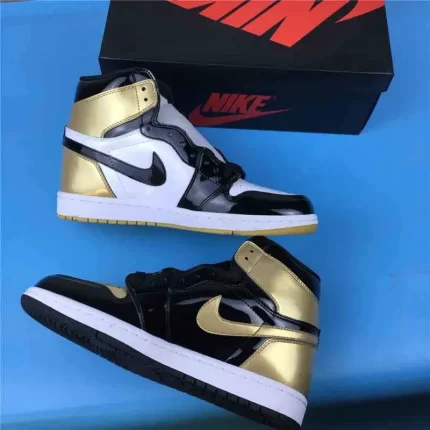 A pair of black, gold, and white high-top sneakers next to a black box.