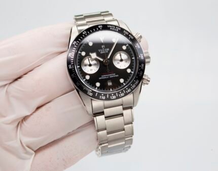 A wristwatch with a black dial and metal bracelet on a person's wrist.