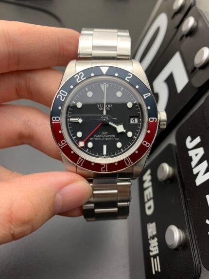 A silver wristwatch with a red and blue bezel and a silver bracelet.