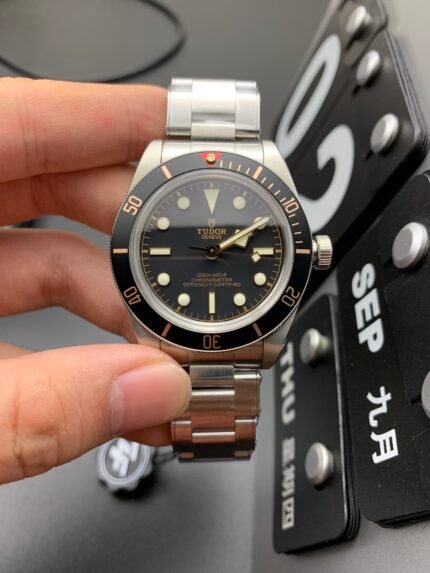 A wristwatch with a black dial and metal bracelet placed on a surface.