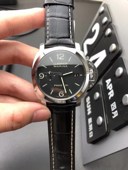 A person holding a black wristwatch with white markers and a black strap.