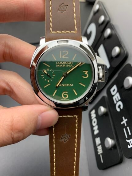 A person holding a green-faced wristwatch with a brown leather strap.