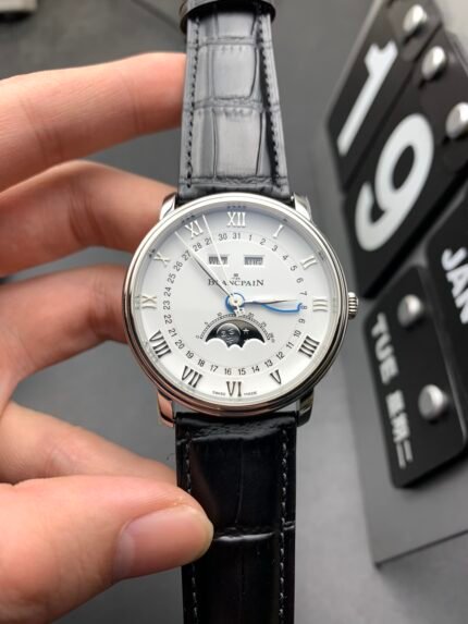 A wristwatch with a white dial, black leather strap, and Roman numerals.