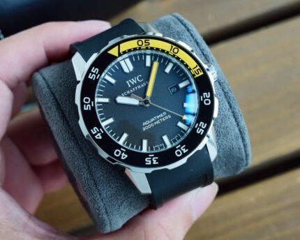 A dark dial watch with a yellow bezel ring and a date window.