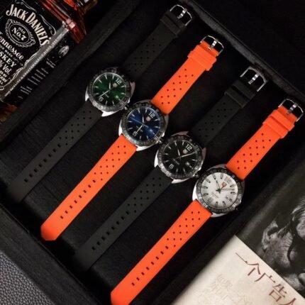 Three wristwatches with black dials and colorful straps displayed on a red stand.