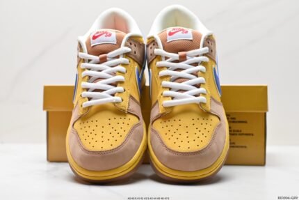 A pair of yellow and blue Nike Dunk Low sneakers with a yellow shoebox in the background.