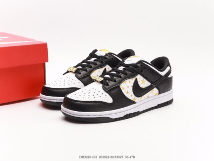 A pair of black and white Nike Dunk Low sneakers with gold stars and a red shoebox.