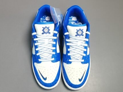 A pair of blue and white Nike Dunk Low sneakers with intricate designs and the number "75" on the tongue.