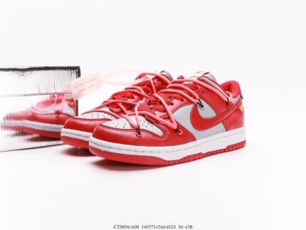 A pair of red and white Nike Dunk Low sneakers with red laces, placed next to a shoebox.