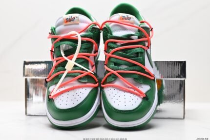A pair of green and white Nike Dunk Low sneakers with orange laces, placed in front of a shoebox.