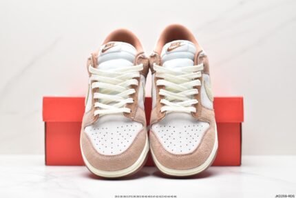 A pair of beige and white Nike Dunk Low sneakers with a red Nike shoebox behind them.