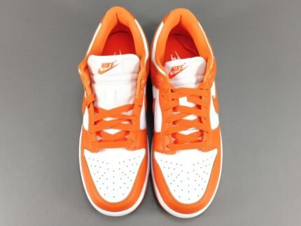 A pair of orange and white Nike Dunk Low sneakers on a gray background.
