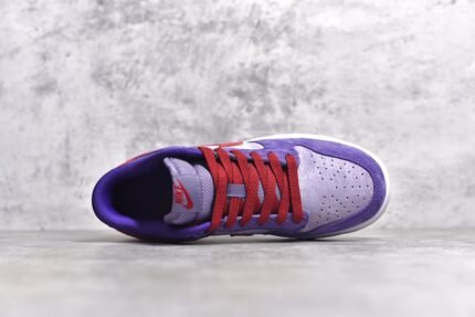 A pair of purple and red Nike Dunk Low sneakers on a gray background.