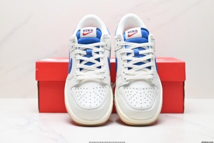 A pair of white and blue Nike Dunk Low sneakers in front of a red Nike shoebox.
