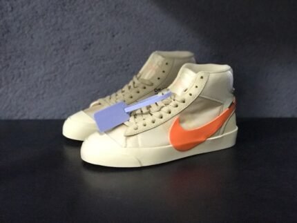 A pair of white high-top sports shoes with orange accents and a blue tag