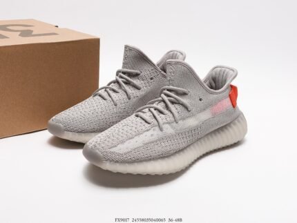 Gray sports shoes with orange accents next to a shoebox.