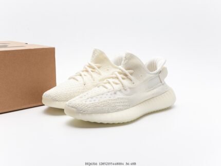 The image features a pair of pure white sneakers with a Primeknit upper that displays a seamless knit texture, enhancing breathability and comfort. The laces are also white, blending seamlessly with the upper for a minimalist design. The sole is made of white Boost material, renowned for its superior energy return and cushioning, offering the wearer an ultimate comfort experience. The modern and stylish design of these shoes makes them suitable for casual daily wear or sports activities.