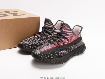 Black sports shoes with red details, next to a shoebox.