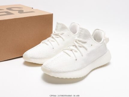 A pair of white sports shoes next to a shoebox.