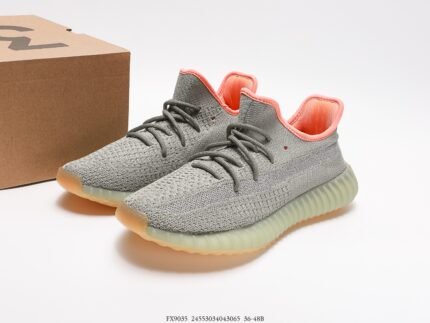 The image showcases a pair of gray sneakers with a Primeknit upper that offers excellent breathability and a snug fit. The laces are gray, coordinating with the upper for a minimalist design. The sole is translucent light green, creating a soft contrast with the upper and featuring Boost technology for superior cushioning and comfort. The orange detail on the inner heel adds a pop of color to the overall design. These shoes are suitable for both sportswear and casual daily wear, making them a stylish and functional choice with their modern design and comfortable fit.