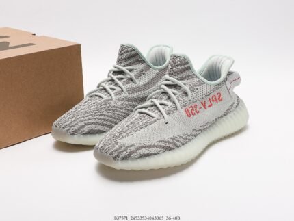 The image showcases a pair of gray knit sneakers with a Primeknit upper that offers great breathability and comfort. The side of the shoe features the red "SPLY-350" text, adding a striking contrast to the design. The sole is white and made with Boost technology, known for its superior energy return and cushioning. The modern and stylish design of these shoes makes them suitable for everyday wear or athletic activities.