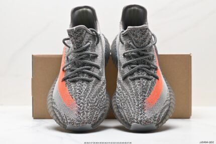 The image displays a pair of gray sneakers with a Primeknit upper that showcases a fine texture. A striking orange stripe adorns the side of the shoes, adding vibrancy and a fashionable touch. The laces are color-coordinated with the upper, and the overall design is simple and contemporary. The outsole is dark and features a distinctive pattern designed for good cushioning and traction. These shoes are suitable for various casual occasions, and their comfort and style make them an ideal choice for everyday wear.