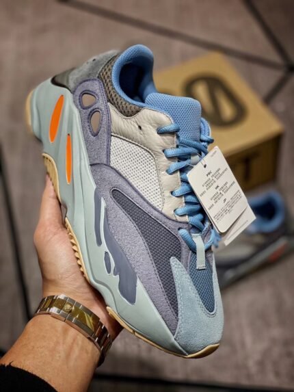 Holding light blue and grey sneakers with branded shoebox in the background