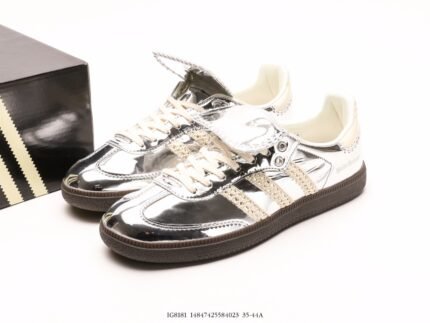 Silver sneakers with three stripes decoration next to a branded shoebox