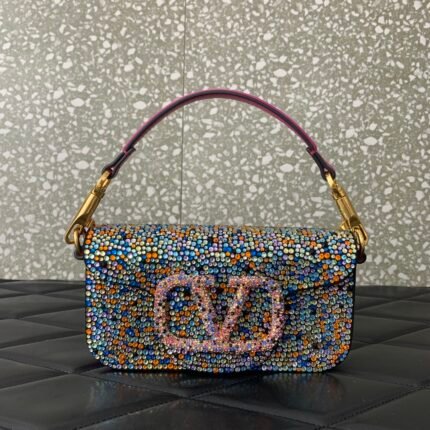 A handbag adorned with colorful beads, featuring a metallic letter logo and a purple handle.