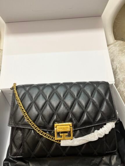 Black quilted handbag with gold chain, on a white background