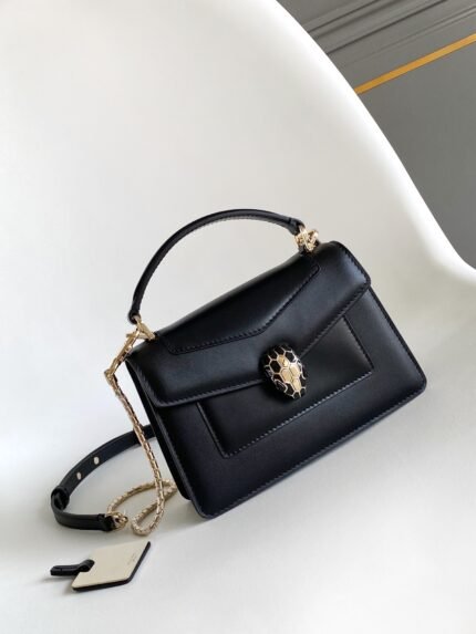 Black handbag with gold chain and snake head decoration.