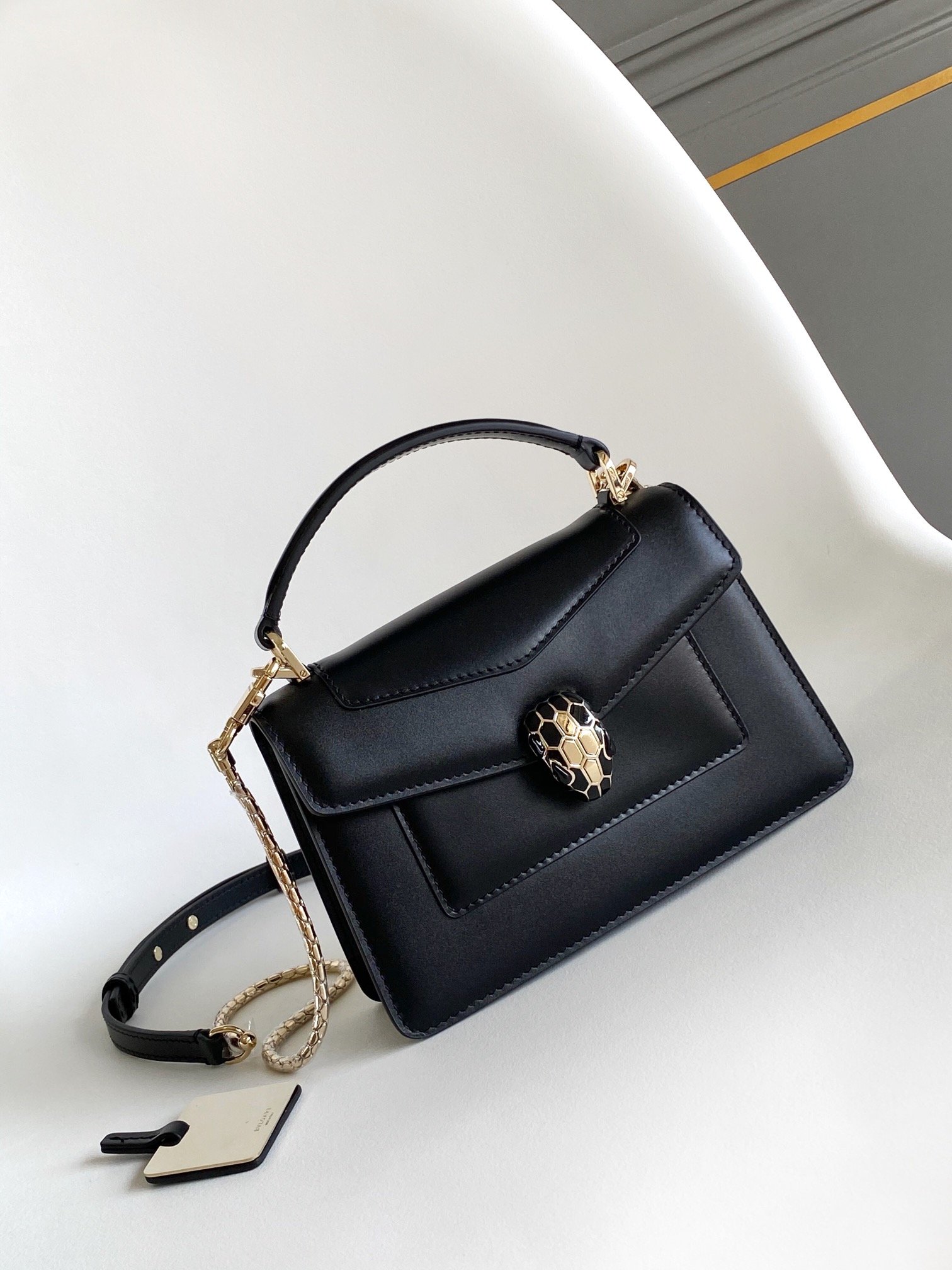 Stylish Black Handbag with Gold Chain and Snake Head Design Black handbag with gold chain and snake head decoration.