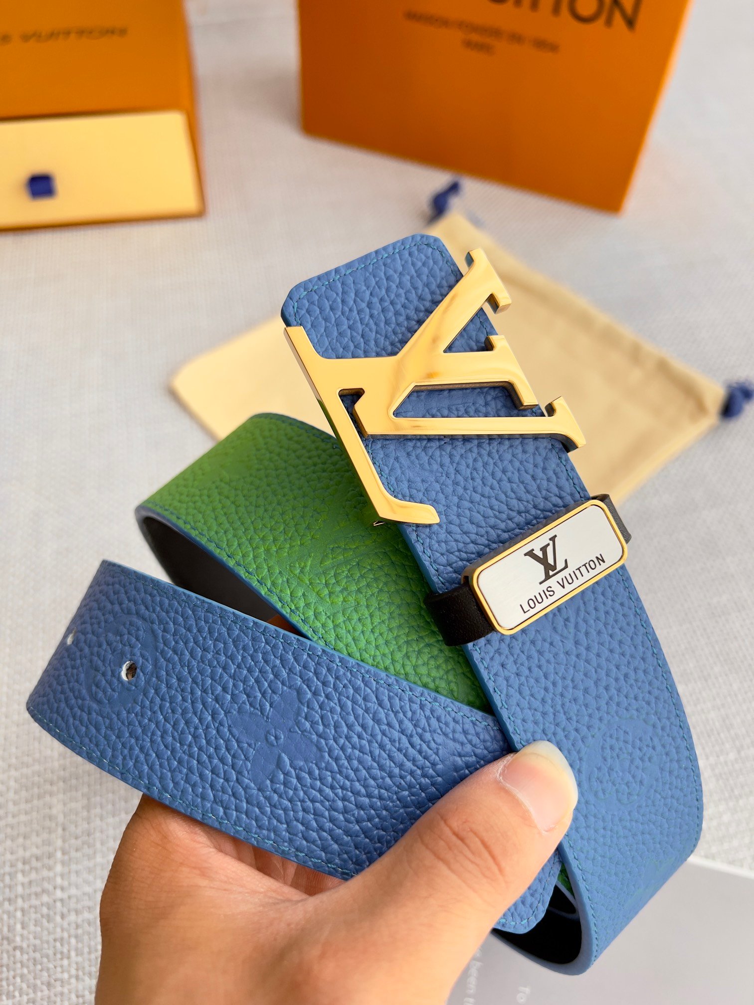 Reversible Leather Belt This is a reversible leather belt with a gold metal buckle, displayed on the brand's elegant packaging.