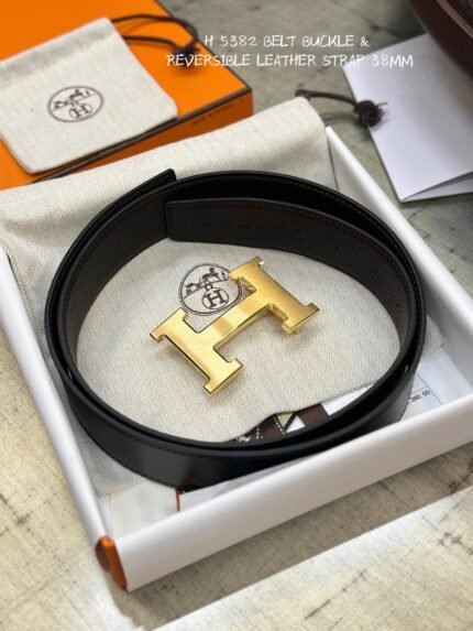 This is a reversible leather belt with a gold metal buckle, displayed on the brand's elegant packaging.