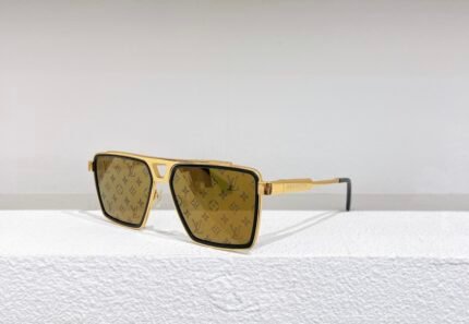 A pair of Louis Vuitton sunglasses with gold frames and patterned lenses, placed on a white surface against a white wall.