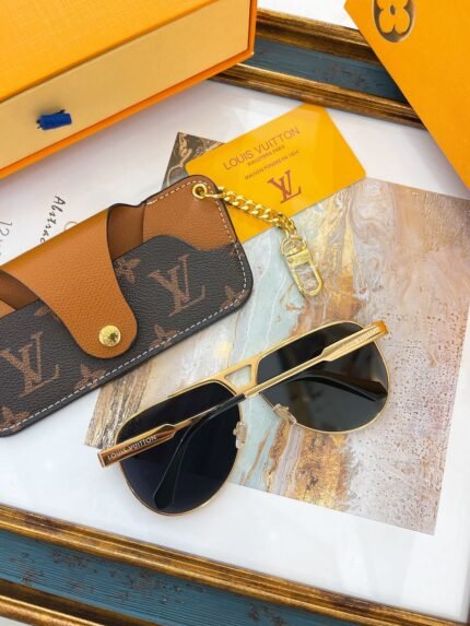A pair of gold-framed Louis Vuitton sunglasses and a Louis Vuitton wallet on a marble surface, with a Louis Vuitton box and card in the background.
