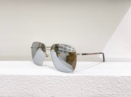A pair of silver metal-framed Gucci sunglasses with reflective lenses, placed on a white surface against a white wall.