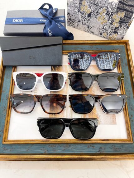 The image shows a collection of stylish sunglasses displayed on a decorative tray. There are multiple pairs with different frame colors, including black, white, and tortoiseshell. In the background, there are Dior branded boxes and a scarf, adding a touch of luxury to the presentation.
