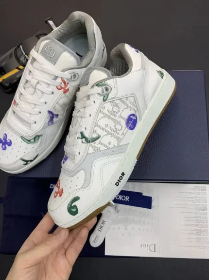 A pair of white sneakers with colorful patterns and letter designs on the surface, with packaging materials beside them.