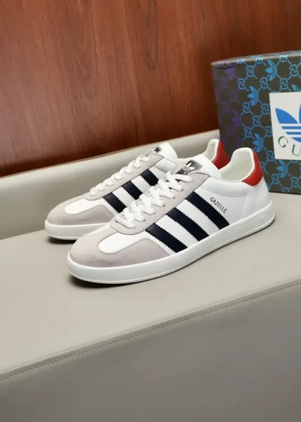 White sneakers with black stripes and red heel, next to a branded box