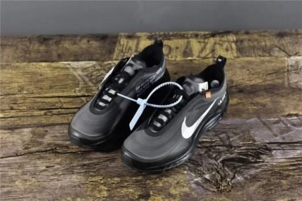 A pair of black sports shoes with white laces, placed on a wooden surface