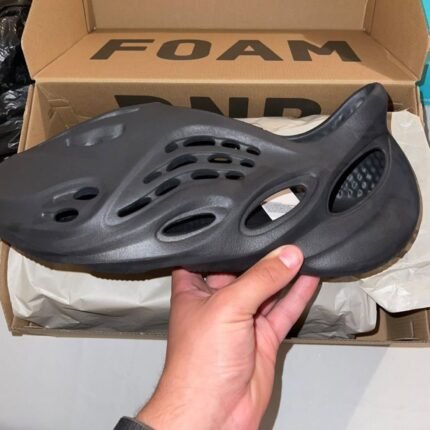 Holding dark grey sneakers with branded shoebox in the background