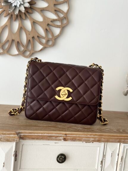 Dark brown quilted handbag with gold chain and clasp, on a wooden table