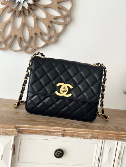 Black quilted handbag with gold chain and clasp, on a wooden table