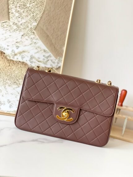 Brown quilted handbag with gold clasp, on a marble surface