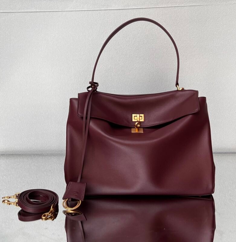 A dark red leather handbag with a detachable shoulder strap and a metal clasp.