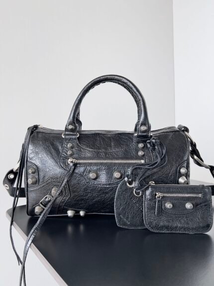 A black leather handbag with a matching wallet, featuring textured leather, metal hardware, and a detachable strap.