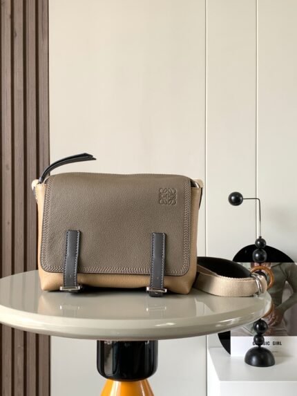 Beige leather crossbody bag with brand logo, placed on a round table